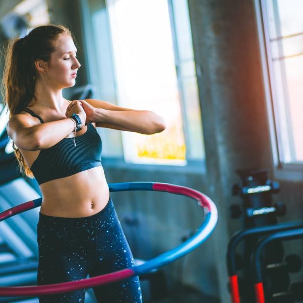 Eine Frau trainiert mit einem Hula-Hoop-Reifen in einem Fitnessstudio.