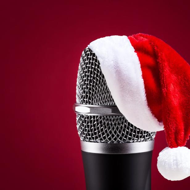 Ein Mikrofon trägt eine rote Weihnachtsmütze vor einem roten Hintergrund.