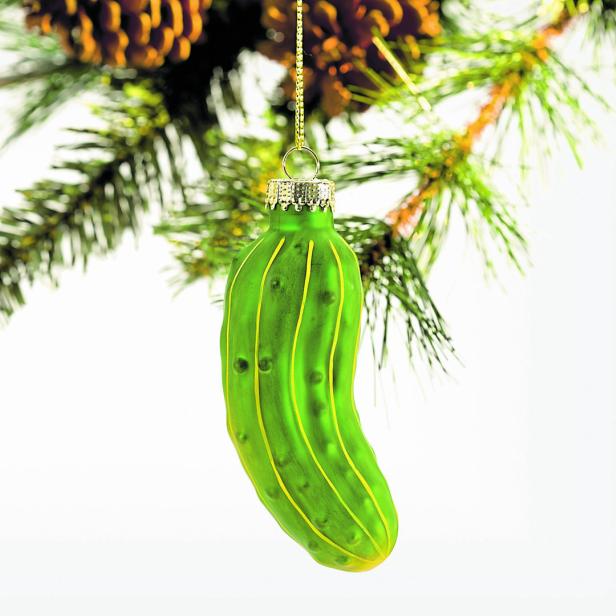 Eine grüne Gurke hängt als Weihnachtsschmuck an einem Tannenzweig.