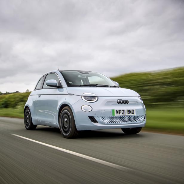 Ein hellblauer Fiat 500 Elektro fährt auf einer Landstraße.