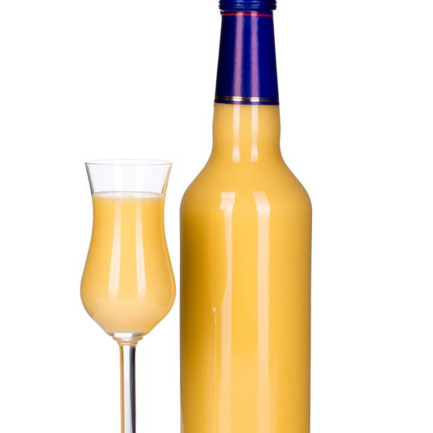 Eine Flasche und ein Glas mit cremigem Eierlikör.
