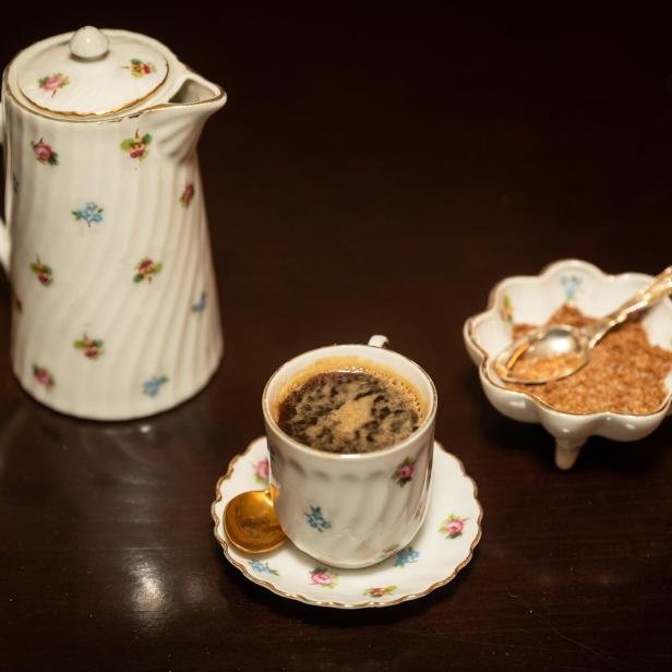 Eine Tasse Kaffee, eine Zuckerdose und eine Kaffeekanne auf einem Tisch.
