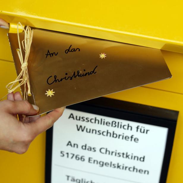 Ein Brief „An das Christkind“ wird in einen gelben Briefkasten in Engelskirchen eingeworfen.