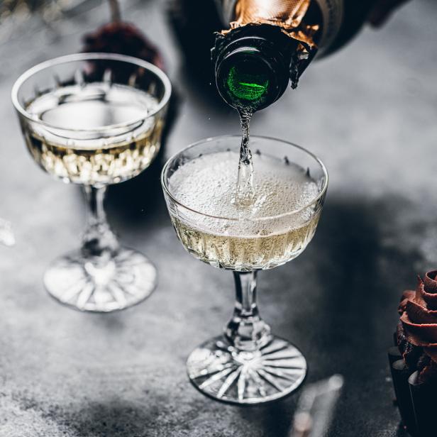 Champagner wird in ein Glas mit einem Schokoladen-Muffin gegossen.