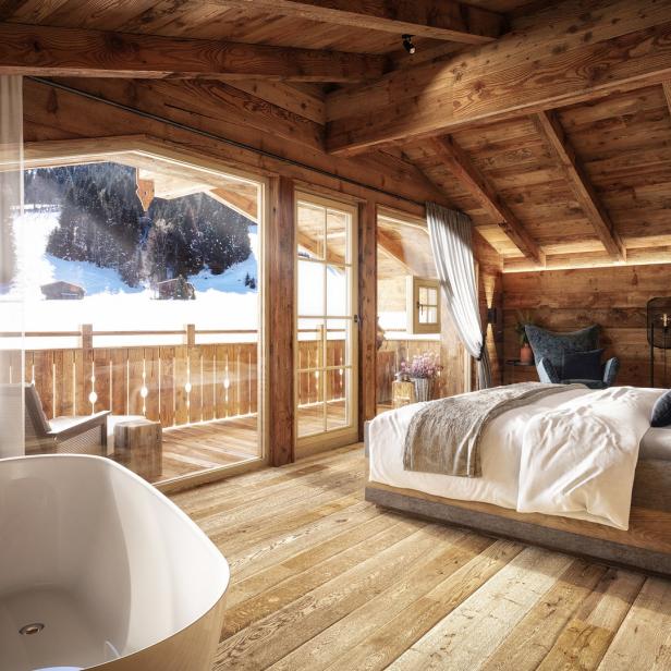 Ein Schlafzimmer im Chalet-Stil mit Holzbalken und Blick auf eine verschneite Landschaft.