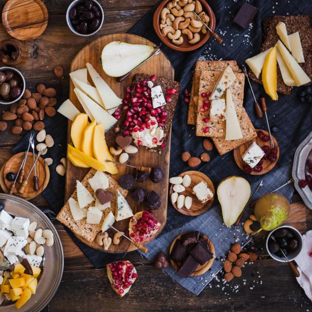 Ein Tisch mit einer Auswahl an Käse, Obst, Nüssen und Brot, arrangiert für eine Mahlzeit.