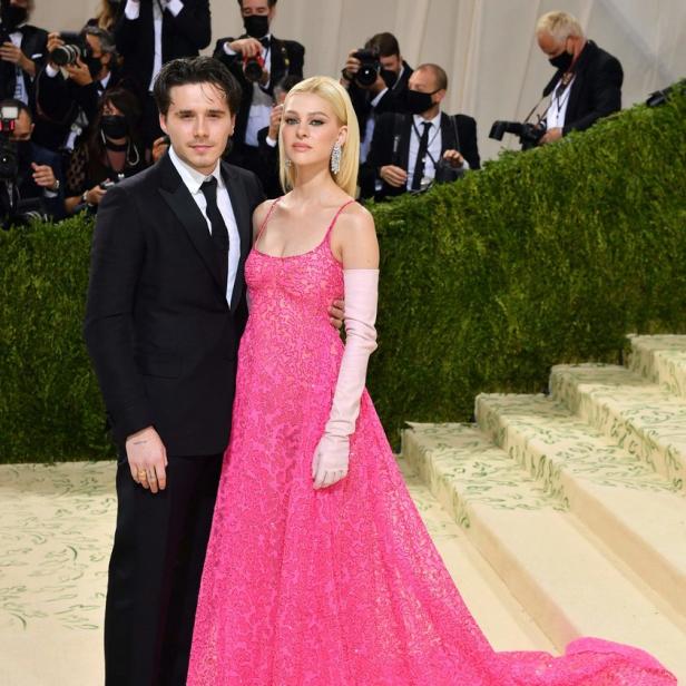 Brooklyn Beckham und Nicola Peltz posieren zusammen; sie trägt ein pinkfarbenes Kleid.