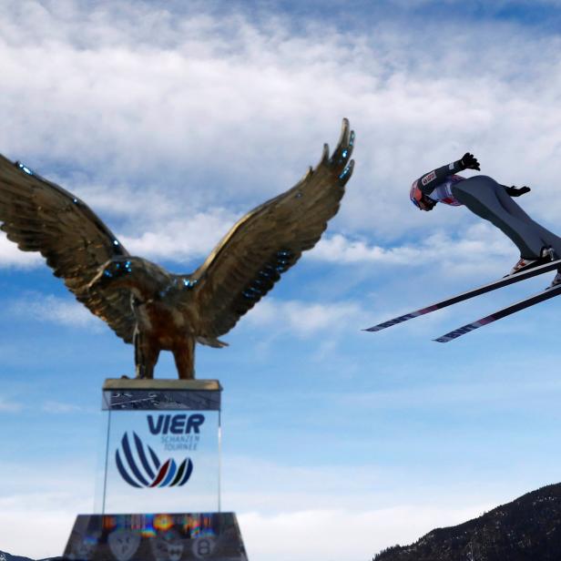 Ein Skispringer in der Luft vor dem Adler-Denkmal der Vierschanzentournee.