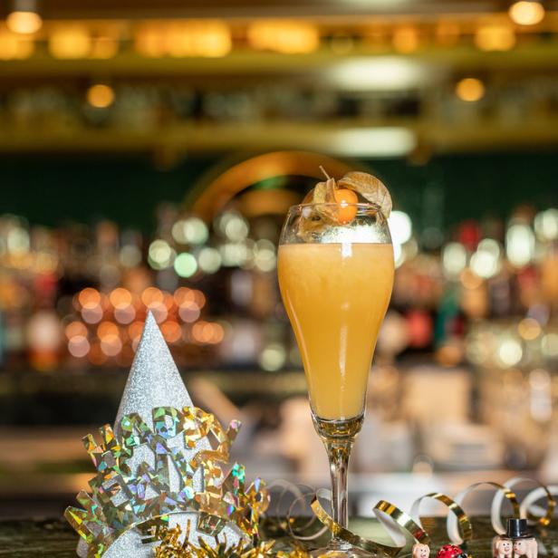 Ein festlicher Cocktail mit Hütchen und Glücksbringern auf einer Bar.
