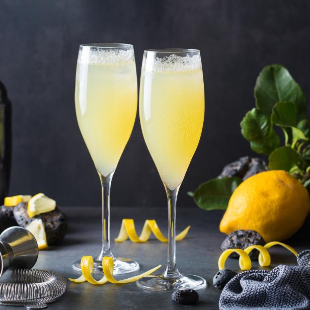 Zwei Gläser mit einem gelben Cocktail, garniert mit Zitronenschalen.