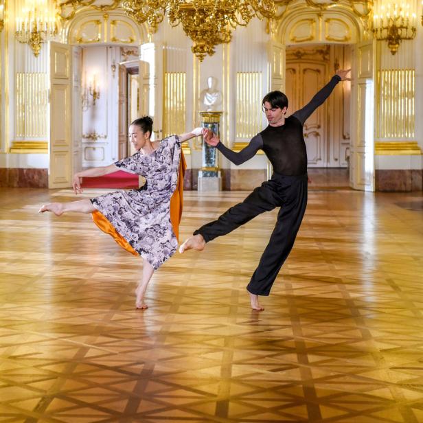 Ein Mann und eine Frau tanzen barfuß in einem prunkvollen Saal.