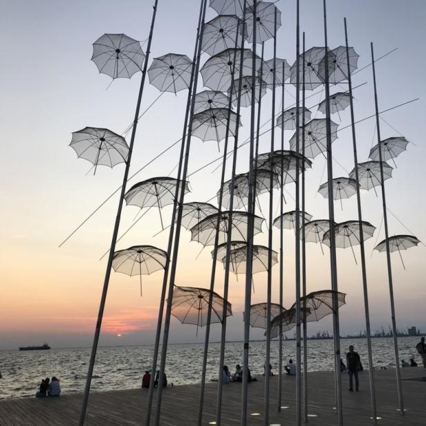 Die Installation „Regenschirme“ am Ufer von Thessaloniki bei Sonnenuntergang.