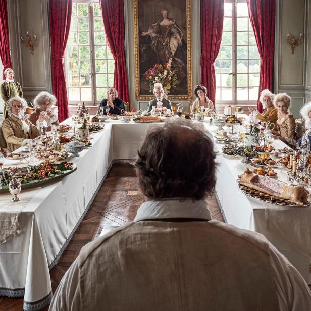 Eine festliche Tafelrunde mit Personen in historischer Kleidung in einem opulenten Saal.