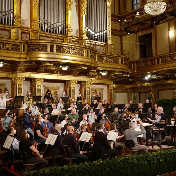Ein Orchester spielt in einem opulenten Konzertsaal mit einer großen Orgel im Hintergrund.