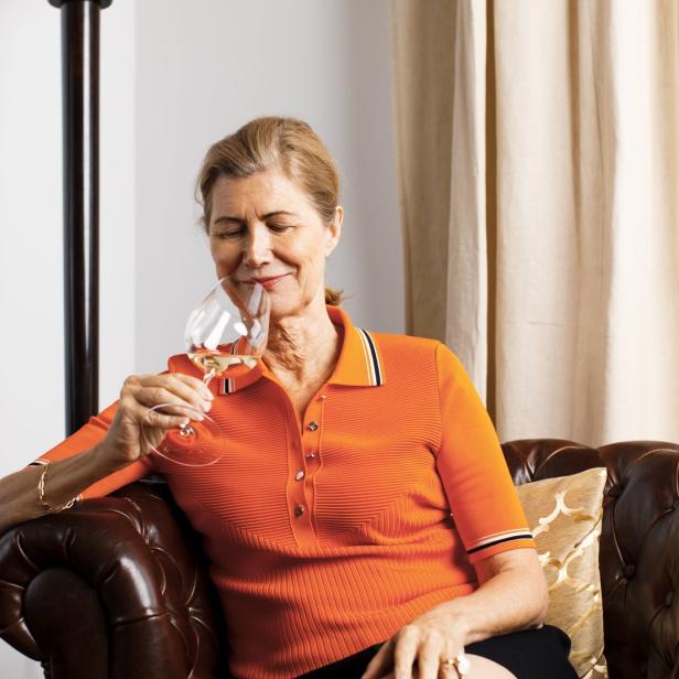 Eine Frau sitzt in einem Ledersessel und genießt ein Glas Weißwein.