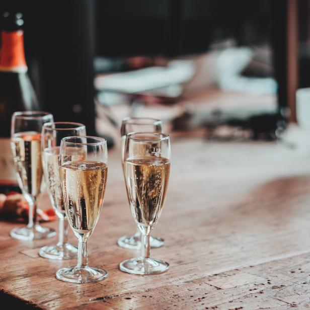 Mehrere mit Sekt gefüllte Gläser stehen auf einem Holztisch.