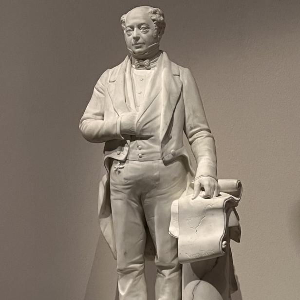 Eine Statue von Lord Brougham in Anzug und mit einer Schriftrolle in der Hand.