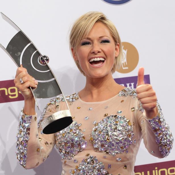 Helene Fischer hält eine Echo-Trophäe und zeigt den Daumen nach oben.