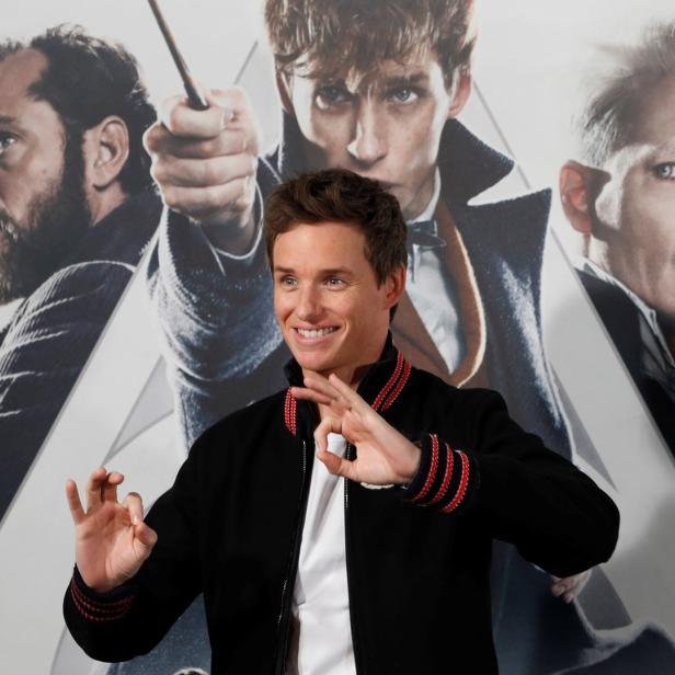 Eddie Redmayne posiert vor einem Poster für „Phantastische Tierwesen“.