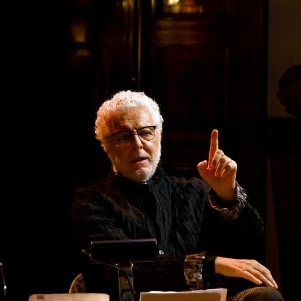 Ein Mann mit weißem Haar und Brille gestikuliert mit erhobenem Zeigefinger.