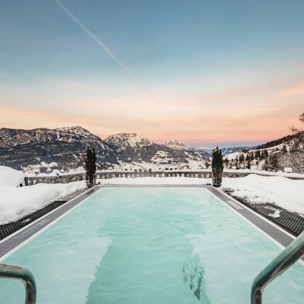 Ein Außenpool mit Blick auf schneebedeckte Berge bei Sonnenaufgang.