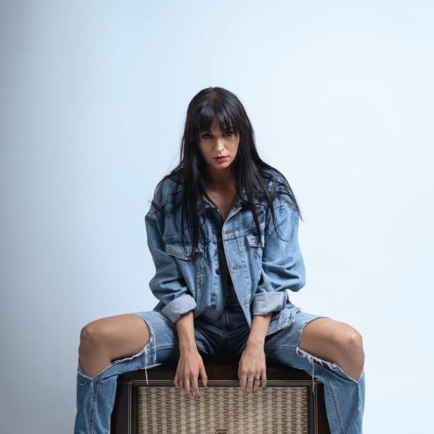 Eine Frau in Jeans sitzt auf einem alten Röhrenradio.