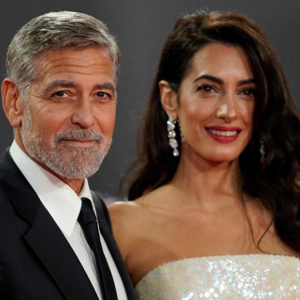 George und Amal Clooney posieren auf einem roten Teppich.