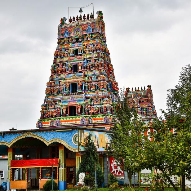 Ein farbenfroher Hindu-Tempel unter einem bewölkten Himmel.
