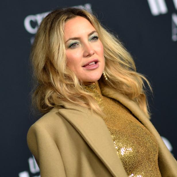 Kate Hudson trägt ein goldenes Paillettenoberteil und einen beigen Mantel.