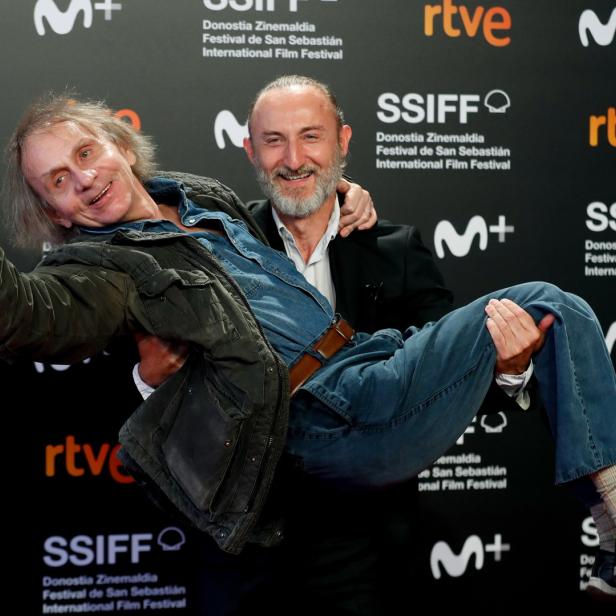 Ein Mann trägt einen anderen Mann auf dem roten Teppich des San Sebastián Film Festivals.