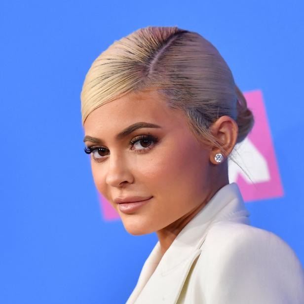 Kylie Jenner posiert auf einem blauen Teppich mit weißem Blazer.
