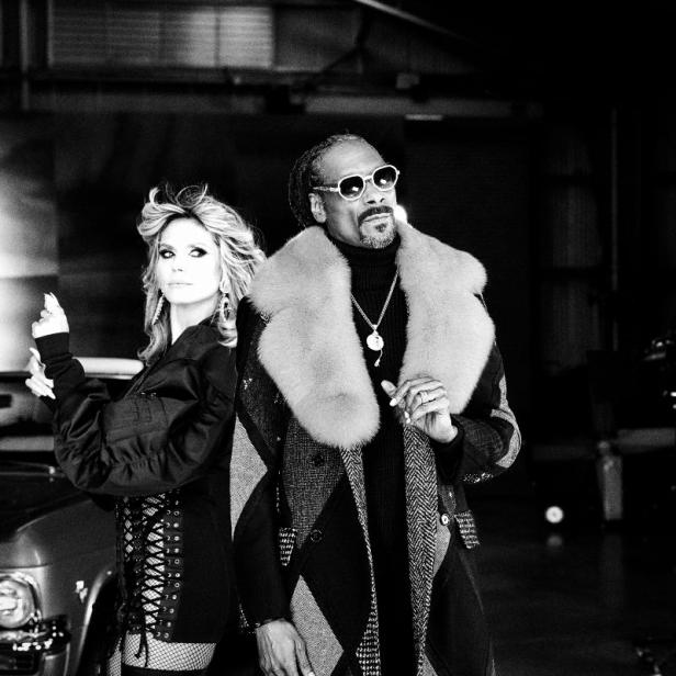Heidi Klum und Snoop Dogg posieren vor einem Oldtimer in Schwarzweiß.