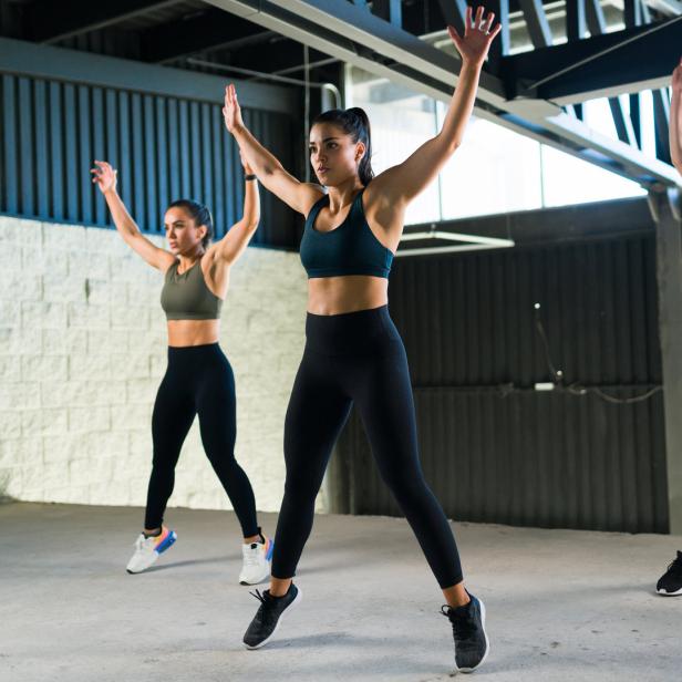 Drei Frauen machen im Fitnessstudio Hampelmänner.