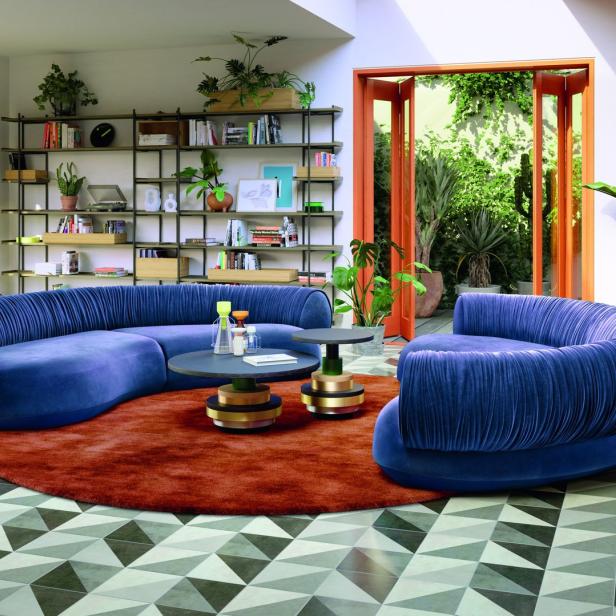 Ein Wohnzimmer mit einem blauen Sofa, einem Sessel und einem runden Teppich.