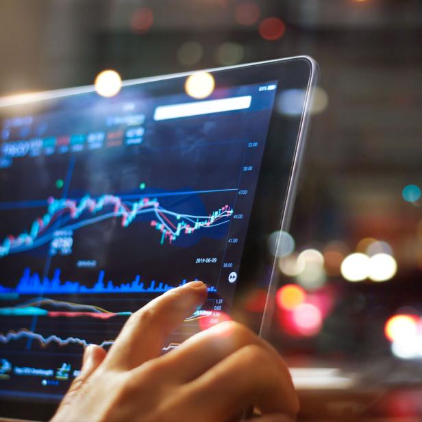 Businessman checking stock market data on tablet on night background