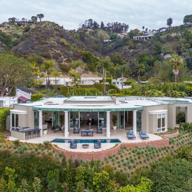 Ein modernes Haus mit Pool liegt auf einem Hügel, umgeben von üppiger Vegetation.