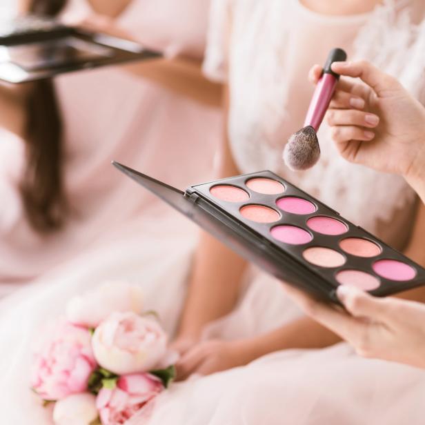 Eine Frau hält eine Palette mit Rouge und einen Pinsel in der Hand.