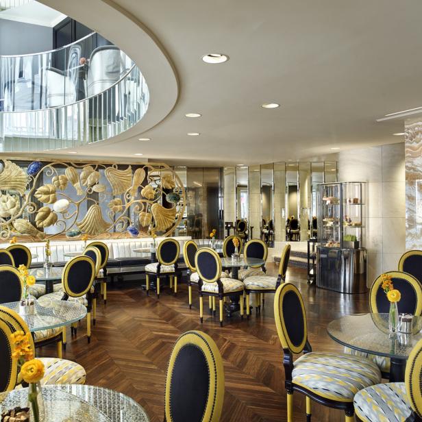 Ein elegantes Café mit Tischen und Stühlen in Gelb- und Schwarztönen.