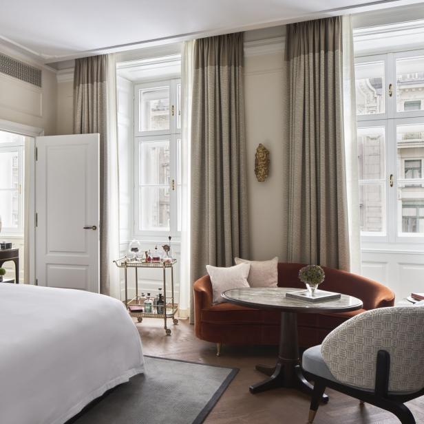 Ein Hotelzimmer mit einem Bett, einem Sofa, einem Tisch und einem Servierwagen.