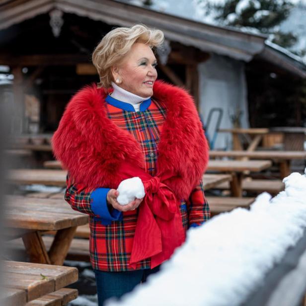 Eine Frau in Winterkleidung hält einen Schneeball in der Hand.
