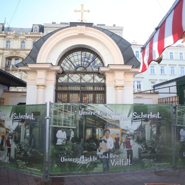 Ein Blick auf den Naschmarkt in Wien, teilweise durch einen Bauzaun verdeckt.
