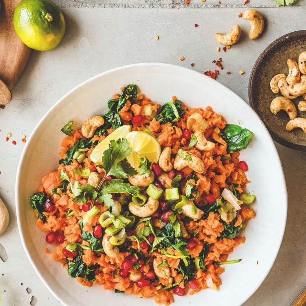 Ein Teller mit Karottensalat, Granatapfelkernen, Cashewnüssen und Limettenstücken.