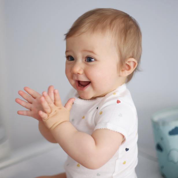 Ein lachendes Baby klatscht in die Hände.