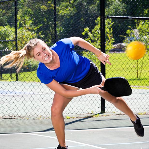 Eine Frau spielt Pickleball auf einem Platz im Freien.