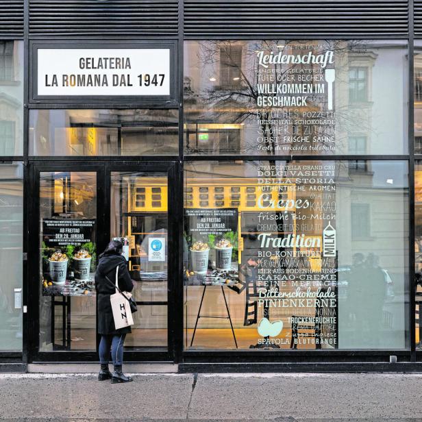 Eine Frau steht vor der „Gelateria La Romana Dal 1947“ und betrachtet die Speisekarte.