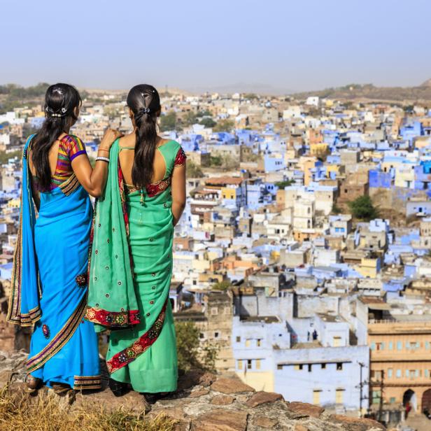 Zwei Frauen in Saris blicken auf die blaue Stadt Jodhpur, Indien.