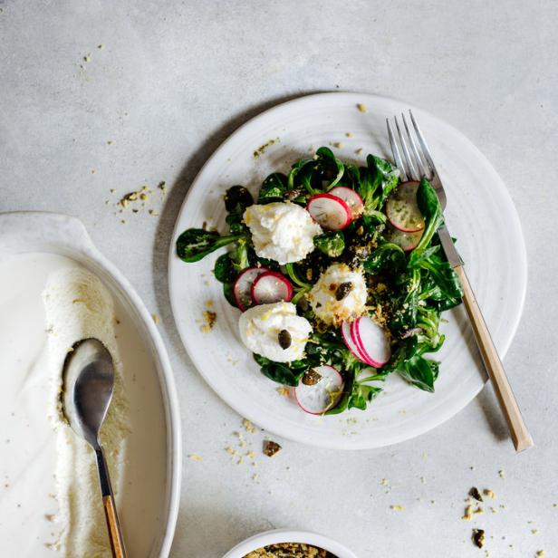 Ein Salat mit Feldsalat, Radieschen und Burrata auf einem Teller.