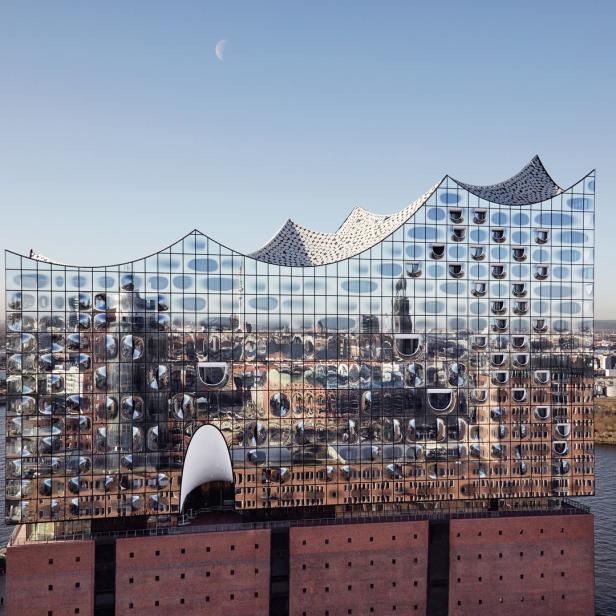 Die Elbphilharmonie in Hamburg unter einem hellblauen Himmel mit einer Mondsichel.