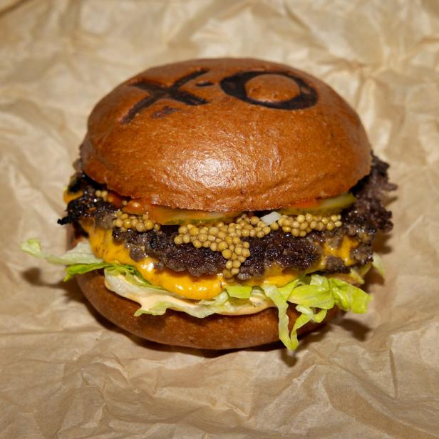Ein Burger mit Salat, Käse, Senf und einem „XO“-Muster auf dem Brötchen.