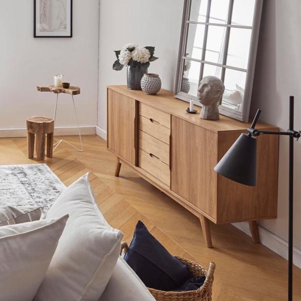 Ein Wohnzimmer mit einem Holzschrank, einem Spiegel und dekorativen Elementen.